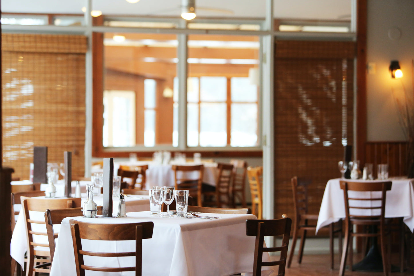 C'est une salle de restaurant. On peut y voir une table blanche, des chaises, des verres à pieds.